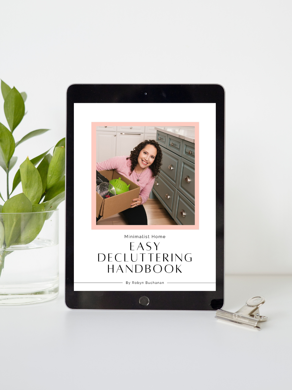 Minimalist Home Easy Decluttering Handbook mockup on ipad sitting on a table that also has a plant and a paperclip