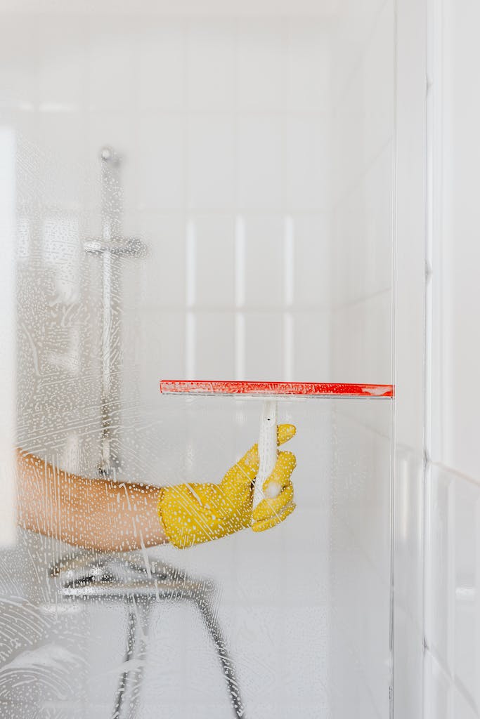 Crop person cleaning glass shower unit. cleaning one thing at a time is a helpful adhd cleaning hack