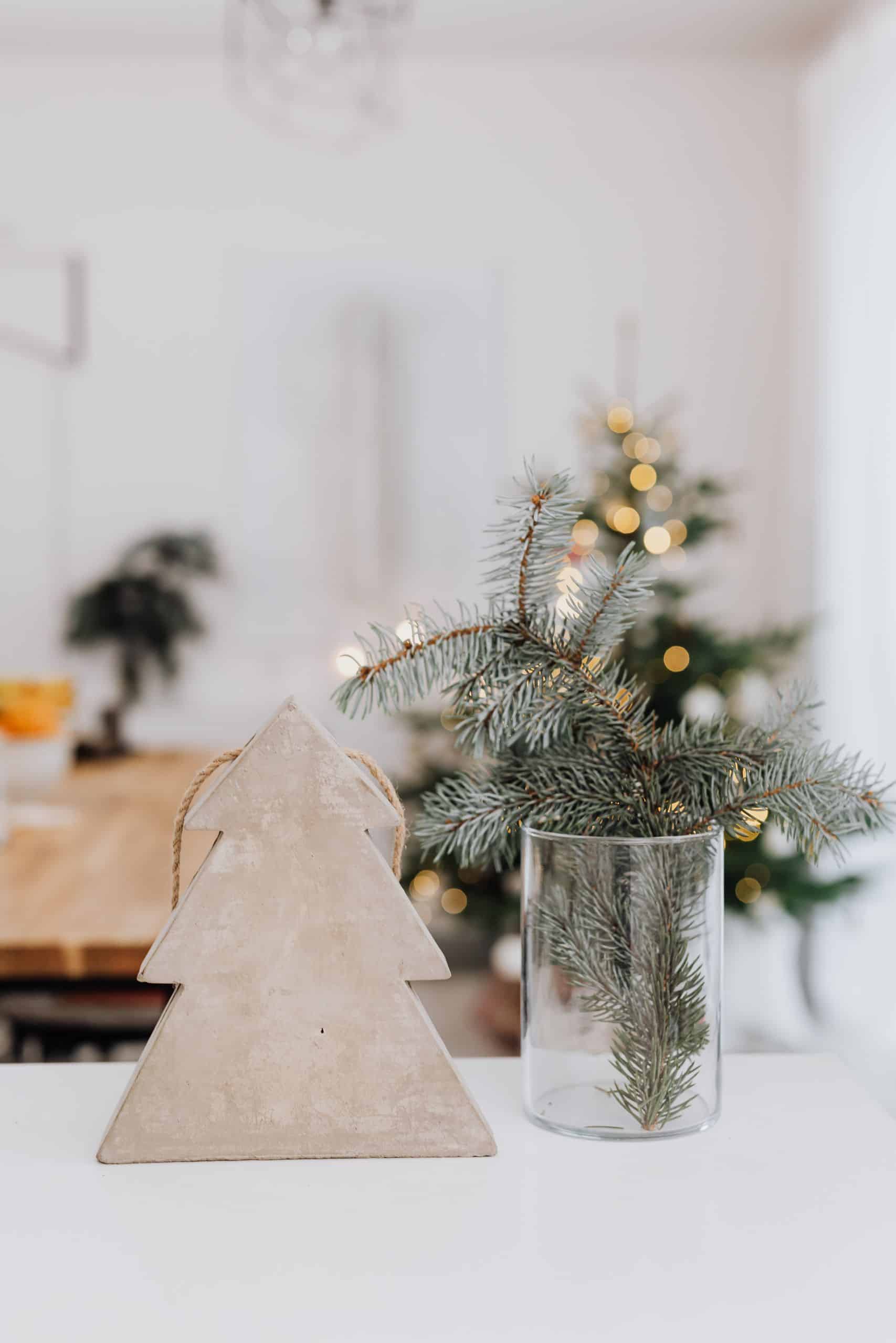 A modern Christmas scene featuring a wooden tree and vase with fir branches.