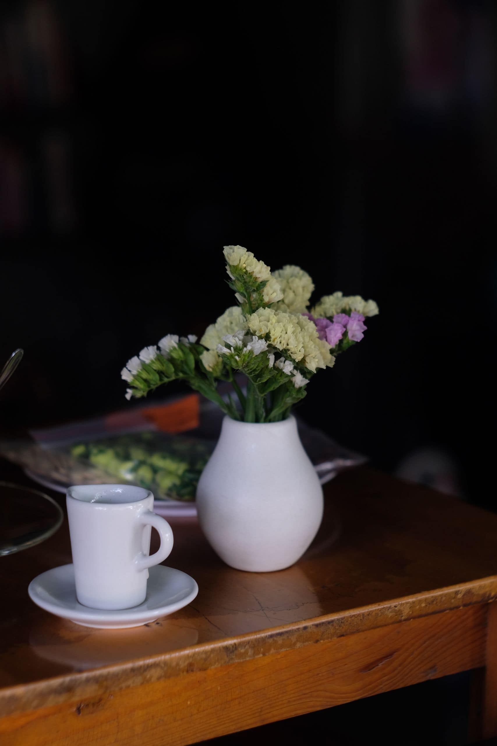 A peaceful scene of flowers in a vase and a coffee cup on a wooden table.