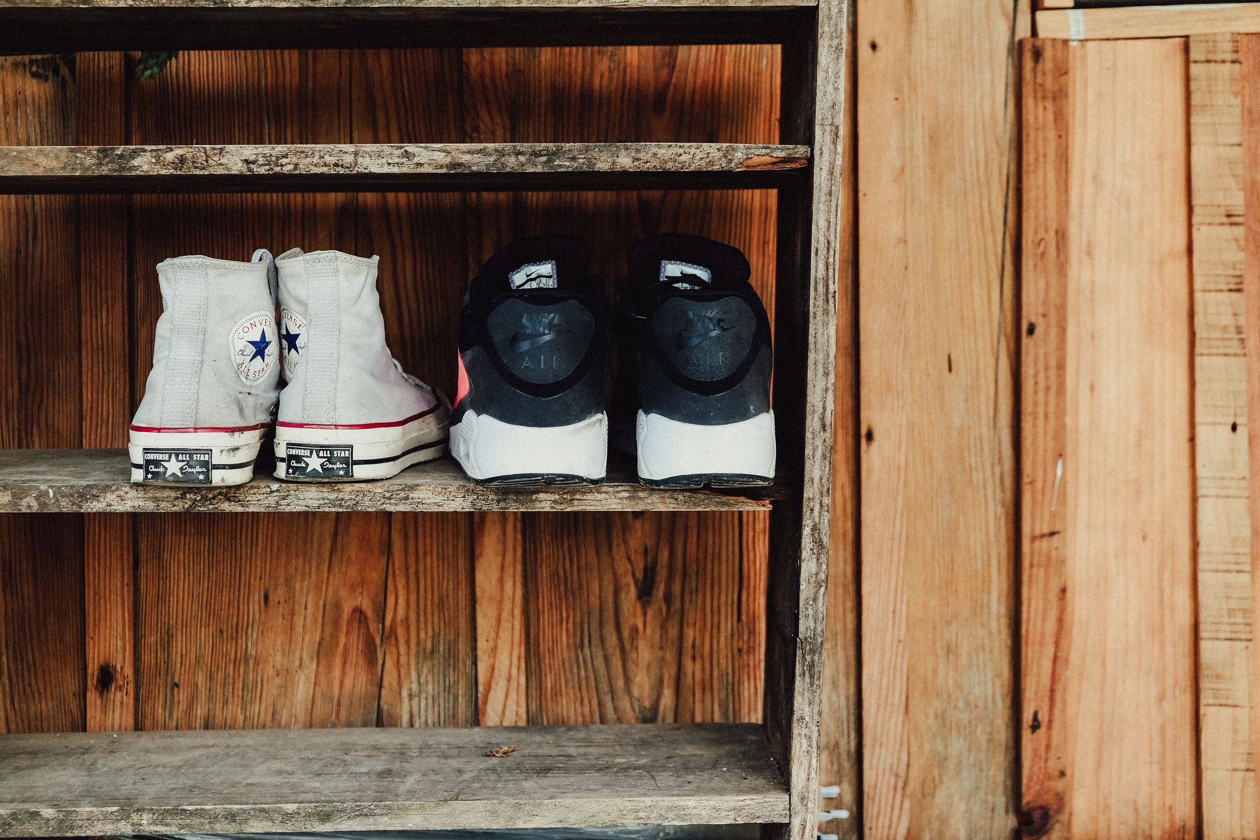 A rustic wooden shelf displaying Converse All Star and Nike shoes, perfect for fashion and vintage themes.