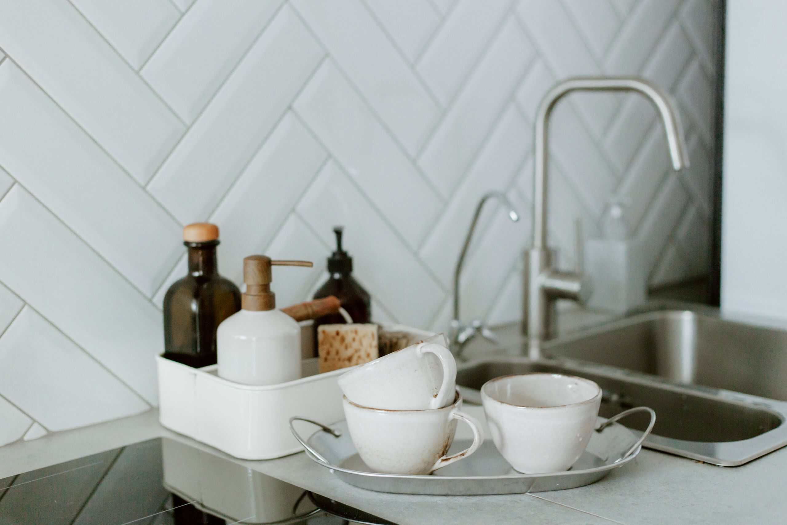 A simple and clean kitchen counter setup featuring tea cups and soap dispensers.