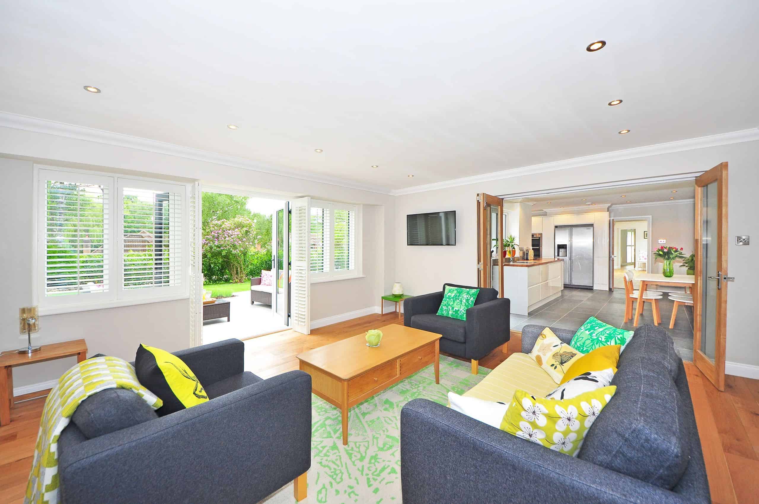 Modern living room with open plan kitchen and garden view, bright and airy ambiance.